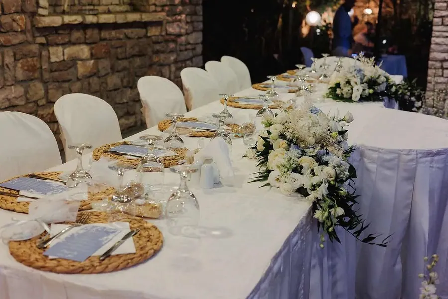 Μακρύ στρωμένο τραπέζι με λευκά λουλούδια