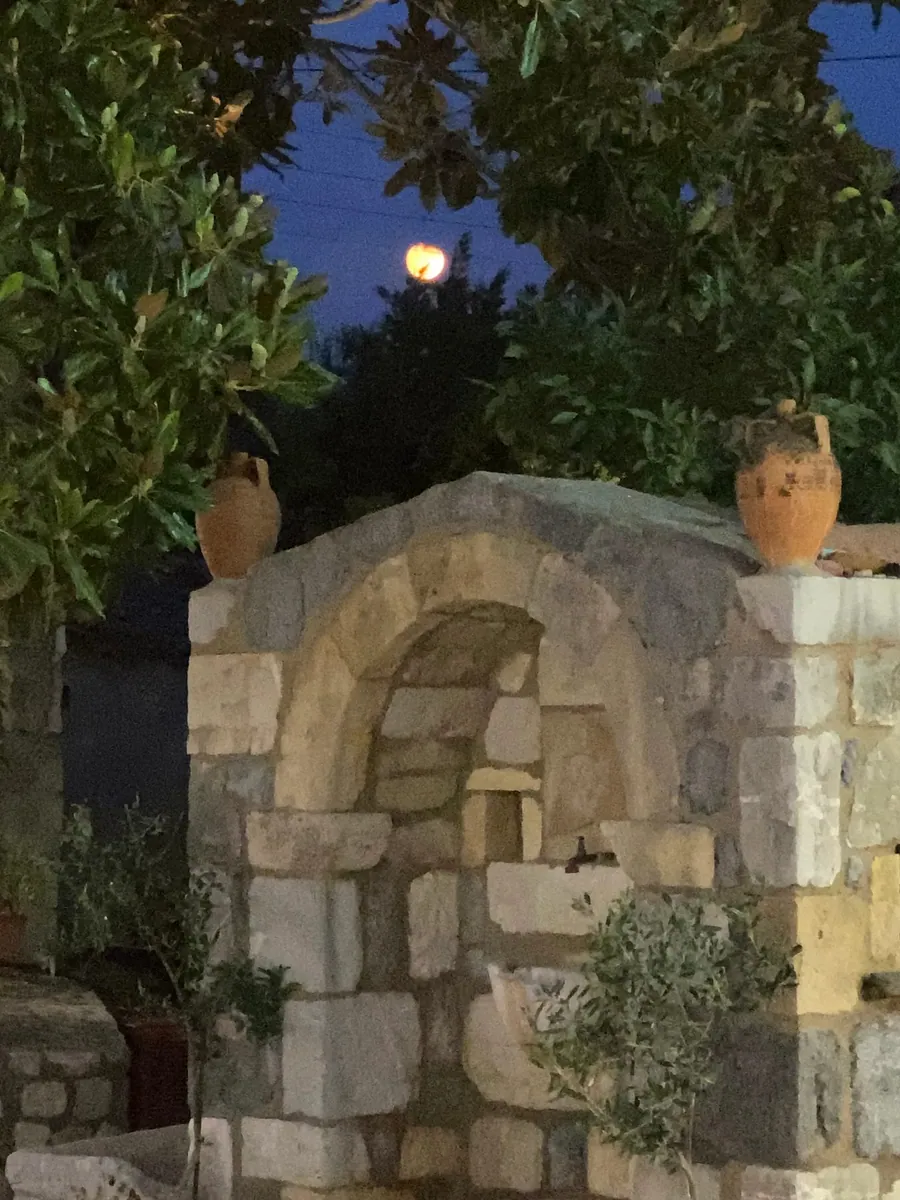Πέτρινο πηγάδι με πιθάρια στον κήπο, το βράδυ
